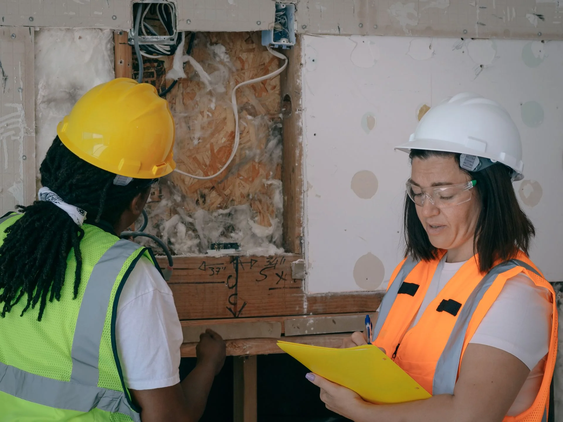 Two tradespeople discussing work in a room under renovation