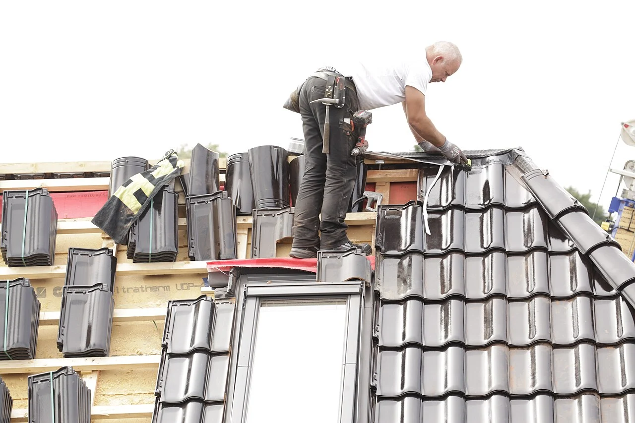 Roofers working around a roof window during tile installation